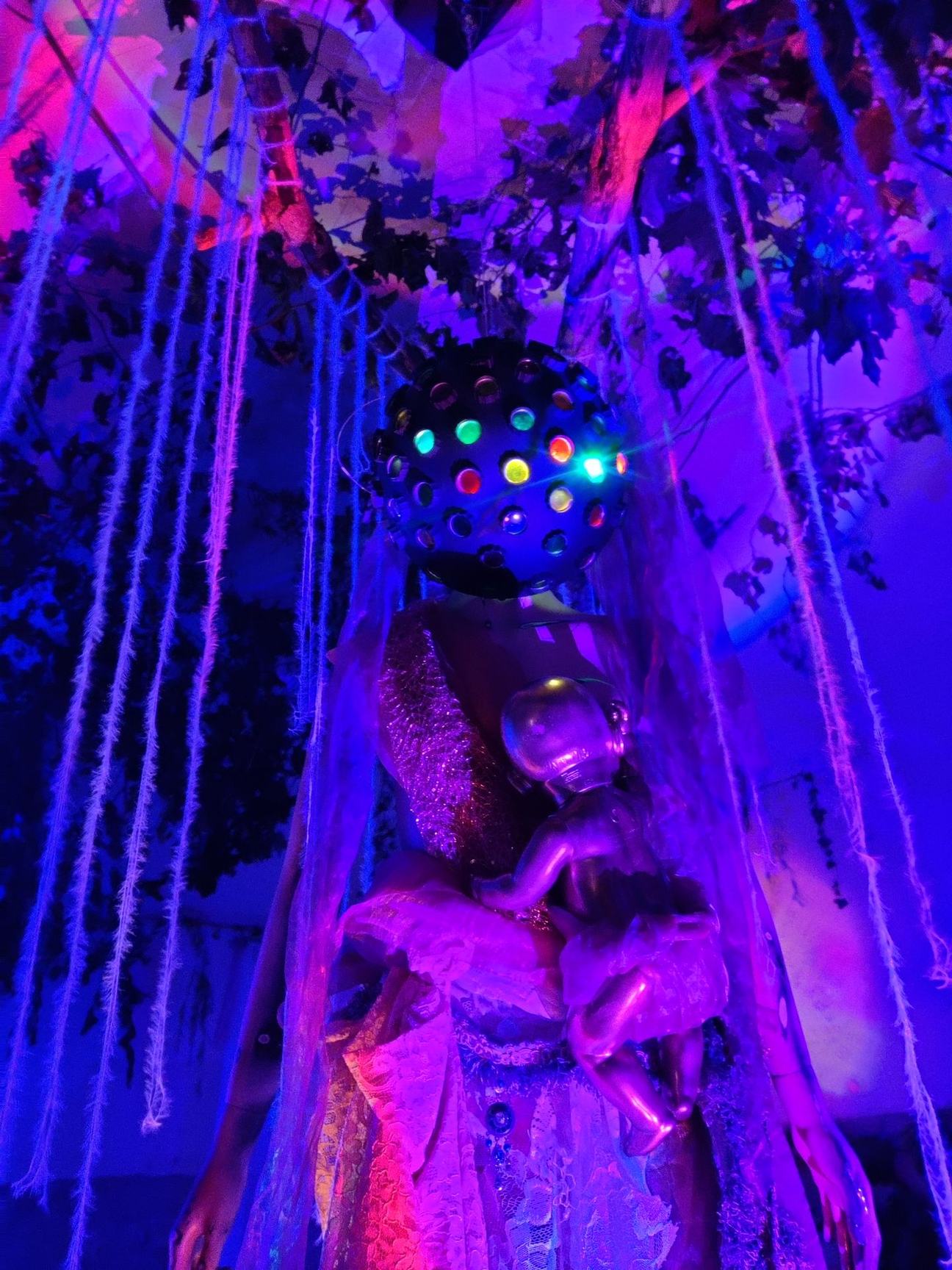 You & me, Space & Time. An immersive, surrealist children’s room centered on a female entity cradling a golden baby—a figure representing the desire for creation and the sanctity of the feminine portal.